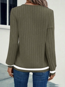 Detail of army green ribbed knit fabric with white striped cuffs and hemline on long sleeve top