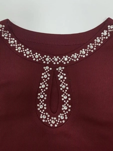 Detail of burgundy ribbed top featuring keyhole neckline and sparkling silver rhinestones
