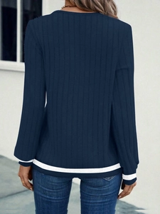 Detail view of navy ribbed knit top showing striped cuffs and hem on the back side