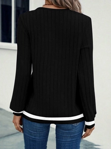 Detail view of black ribbed knit top featuring contrast white stripes on hem and cuffs