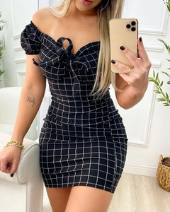 Detail of checkered bodycon dress with off-shoulder neckline and bow-tie decoration