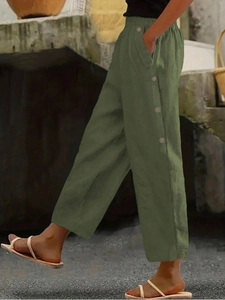 Detail view of army green wide-leg trousers featuring decorative buttons and linen texture