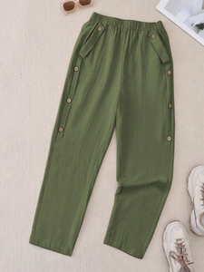Detail of dark green cotton linen pants featuring elastic waist and retro decorative buttons