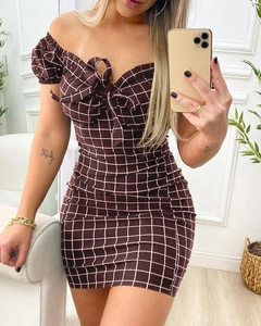 Detail of off-shoulder checkered dress featuring front bow tie and elastic puff sleeves