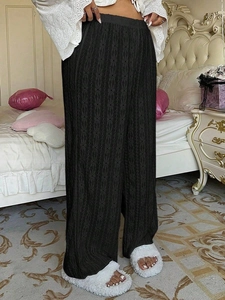 Close-up of black high-waisted wide-leg pants with vertical hollow-out floral patterns