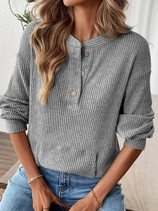 Detail of grey knitted top featuring vertical rib texture and rustic button neckline