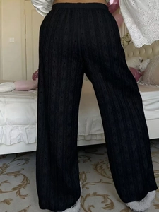Detail of high-waist black wide-leg trousers featuring fine textured jacquard fabric