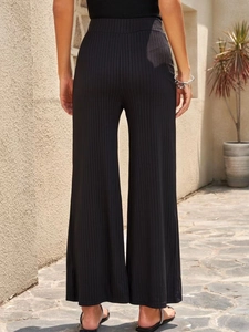 Rear view of black high-waisted ribbed wide-leg pants showing elegant drape and fit
