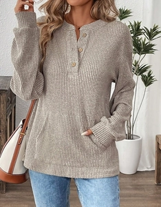 Detail of light brown knit sweater featuring henley neck with wood buttons and pocket