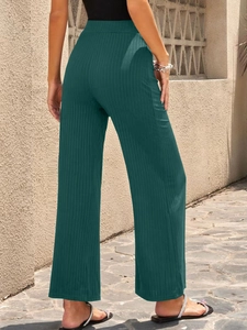 Detail of high-waisted emerald green ribbed wide-leg trousers in breathable stretch fabric