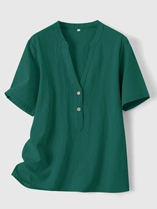 Detail of V-neckline on dark green linen shirt featuring natural wooden buttons