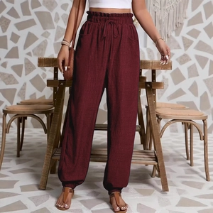 Détail de la taille haute à cordon et du tissu bordeaux texturé sur ce pantalon décontracté