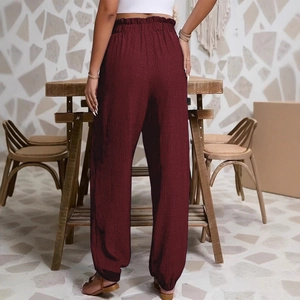 Vue détaillée du pantalon bordeaux à taille élastique et texture de tissu plissé fin