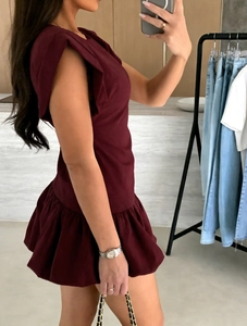 Detail view of burgundy ruffle sleeve dress with pleated skirt and side profile design