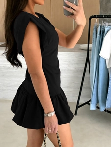 Detail view of the elegant tiered ruffle hem on this black sleeveless mini dress