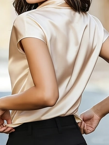 Detail view of champagne satin blouse showing elegant glossy fabric and drape from the side