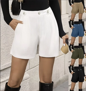Detail of high-waist pleated corduroy shorts featuring decorative buttons and side pockets