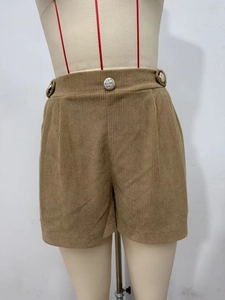 Detailed texture of high-waisted corduroy shorts with decorative gold vintage buttons