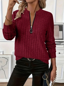 Detail of ribbed knit fabric texture and silver ring zipper on a burgundy long sleeve top