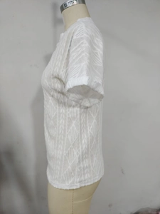Detail of white short sleeve knit top with geometric diamond and vertical hollow patterns