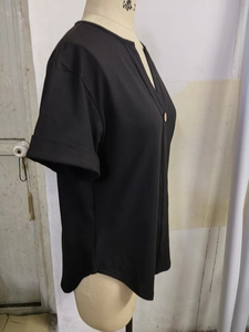 Detail van V-hals met decoratieve knoop op een casual zwart shirt met korte mouwen