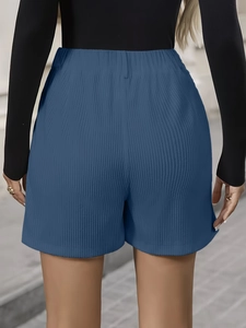 Detail view showing blue high-waisted pleated shorts with vertical corduroy texture