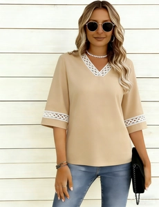 Close-up of elegant V-neckline with white geometric lace embroidery on beige chiffon top