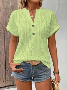 Macro detail of V-neck button closure and cable knit texture on light green summer top
