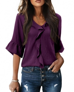 Deep purple V-neck top with ruffled edges and flared sleeves shown on model with jeans