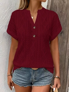 Close-up of deep red V-neck knit top showing the diamond cable texture and button detail