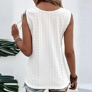 Detail of white eyelet embroidery top with tie-up shoulder straps and geometric patterns
