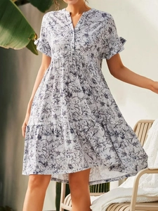 Détail d'une robe trapèze fleurie avec manches à volants et décolleté en V boutonné