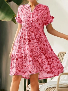 Détail de robe fleurie rose avec col en V boutonné et manches volantées légères