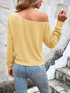 Détail d'un pull jaune à maille ajourée avec une élégante encolure à épaules dénudées