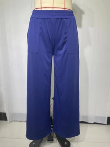 Dettaglio della vita alta elastica e delle tasche applicate sui pantaloni blu a gamba larga