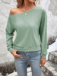 Détail du haut vert à manches longues avec texture évidée et épaule dénudée