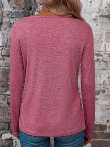 Detail of long-sleeved pink knitted top showing back view against a vintage brick wall