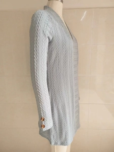 Detail der hellblauen Strickjacke mit Strukturmuster und zwei dunkelbraunen Knöpfen