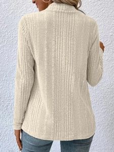 Close-up of light apricot knit cardigan featuring a classic vertical ribbed texture design