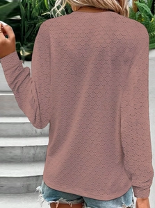 Close-up of pink long-sleeved top featuring hollow dot pattern fabric and round neckline
