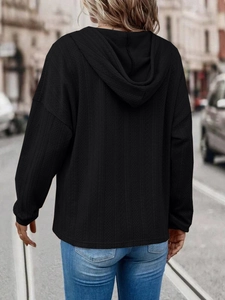 Close-up of black oversized hoodie featuring intricate vertical herringbone jacquard texture