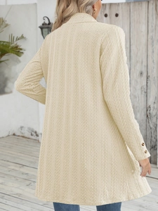 Detail der Zopfstrick-Struktur und dunklen Knöpfe an einer beigefarbenen Strickjacke