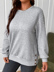 Detail of grey waffle-knit sweatshirt with side buttons and ribbed crew neck texture