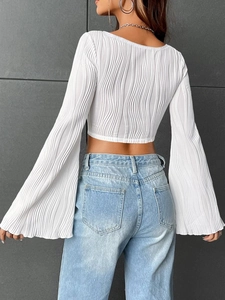 Detailed back view of white accordion pleated crop top with flared bell sleeves and U-neck