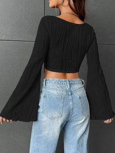 Rear view of black pleated cropped top featuring flared sleeves and slim fit texture