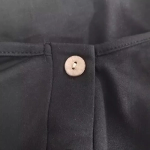 Women's minimalist black sleeveless dress with button detail and dual pockets