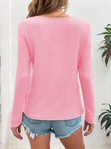 Detail of pink waffle knit texture and long sleeve design on a casual women's top