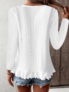 Détail d'un haut blanc à manches longues avec broderie anglaise et ourlet volanté