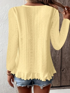 Détail du tissu en maille ajourée jaune pâle et de l'ourlet à volants de ce haut femme