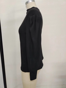Detail of black ribbed knit turtleneck showing puffed shoulder and long cuffed sleeves